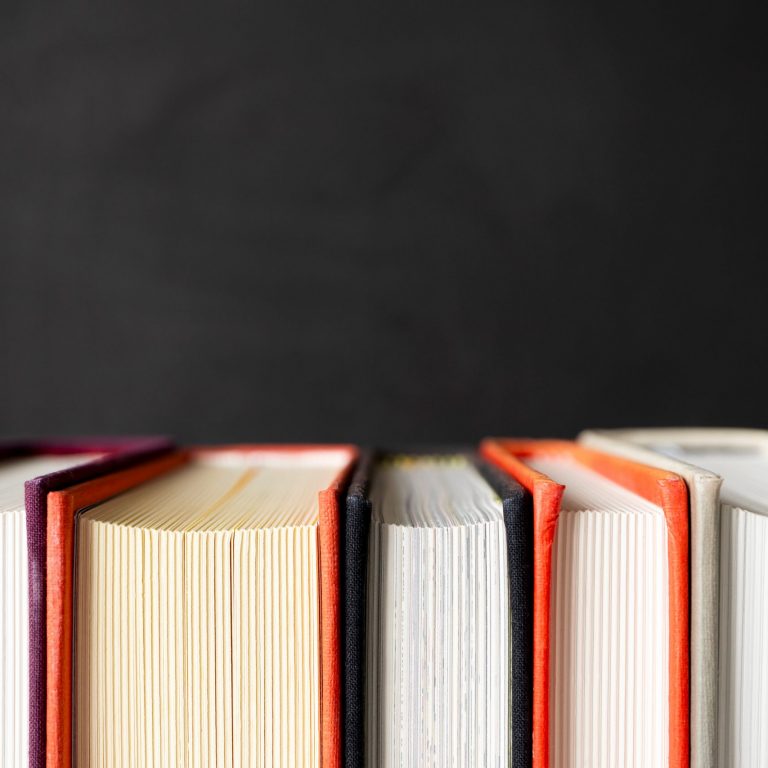 Stack of books with selective focus on black background with copy space. Banner format. Home education, learning and studying